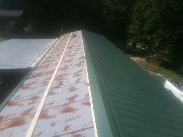 Old rusted panels beside newly installed green metal roofing — Wind Damage Roof Repair by Roofing Brothers in Goodfield