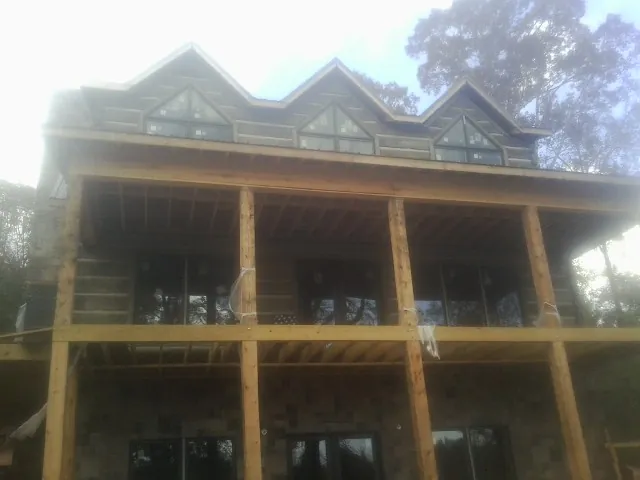 Dormers and porch framing on a large log home under construction — Roof Coating work by our crew in Goodfield