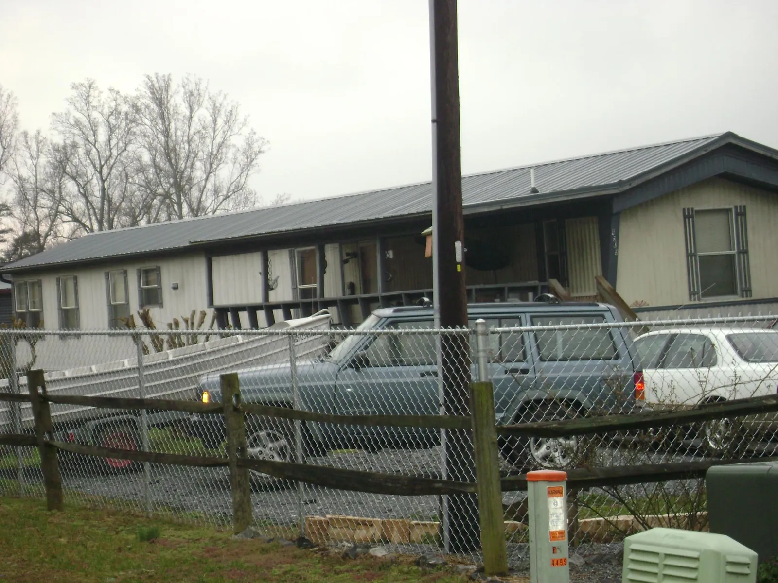 Dark metal roof on a long single story building behind a chain link fence in Goodfield