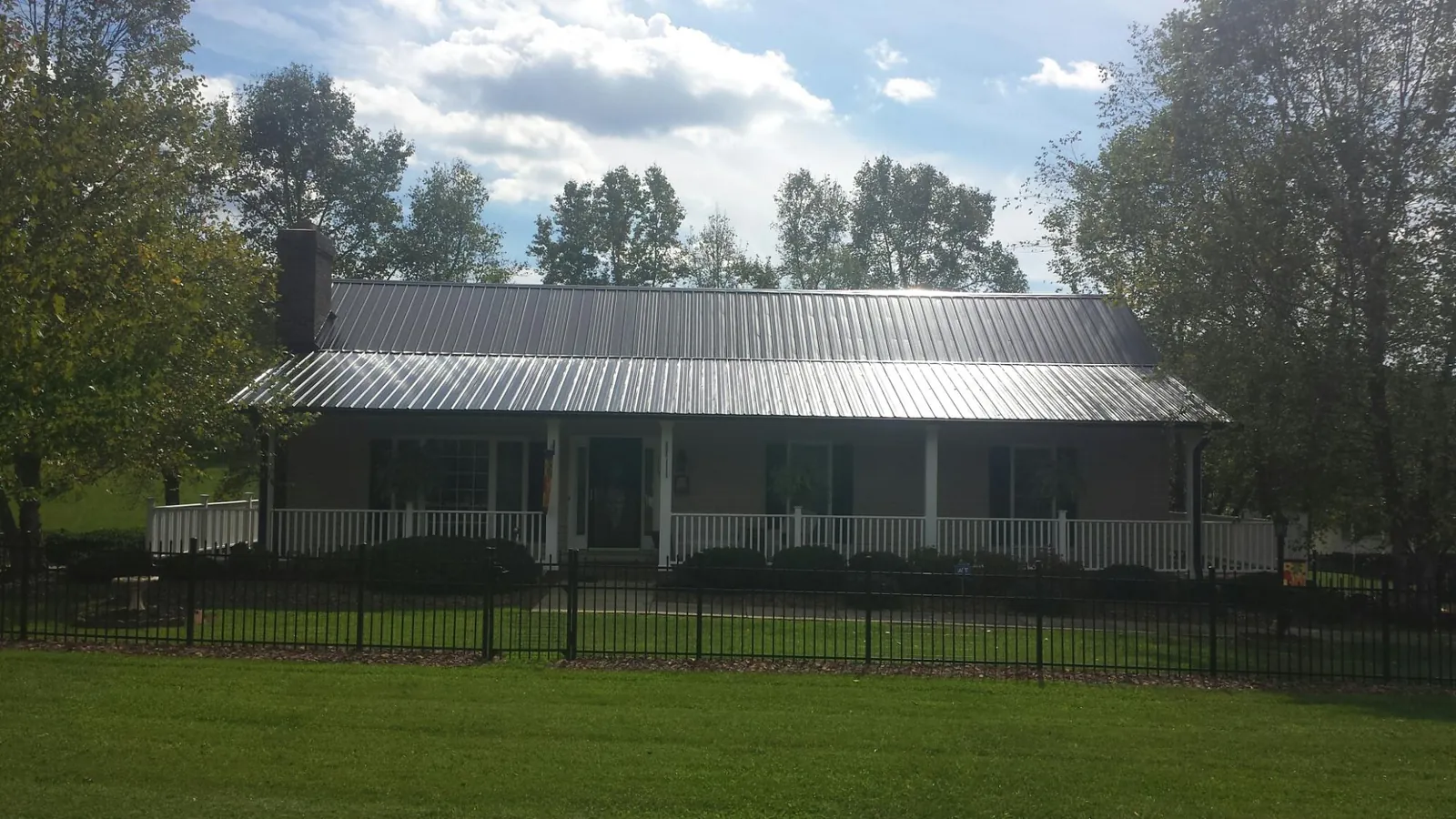 Gray metal roof on a brick ranch with a full width front porch — Gutter Guard Installation work by our crew in Goodfield