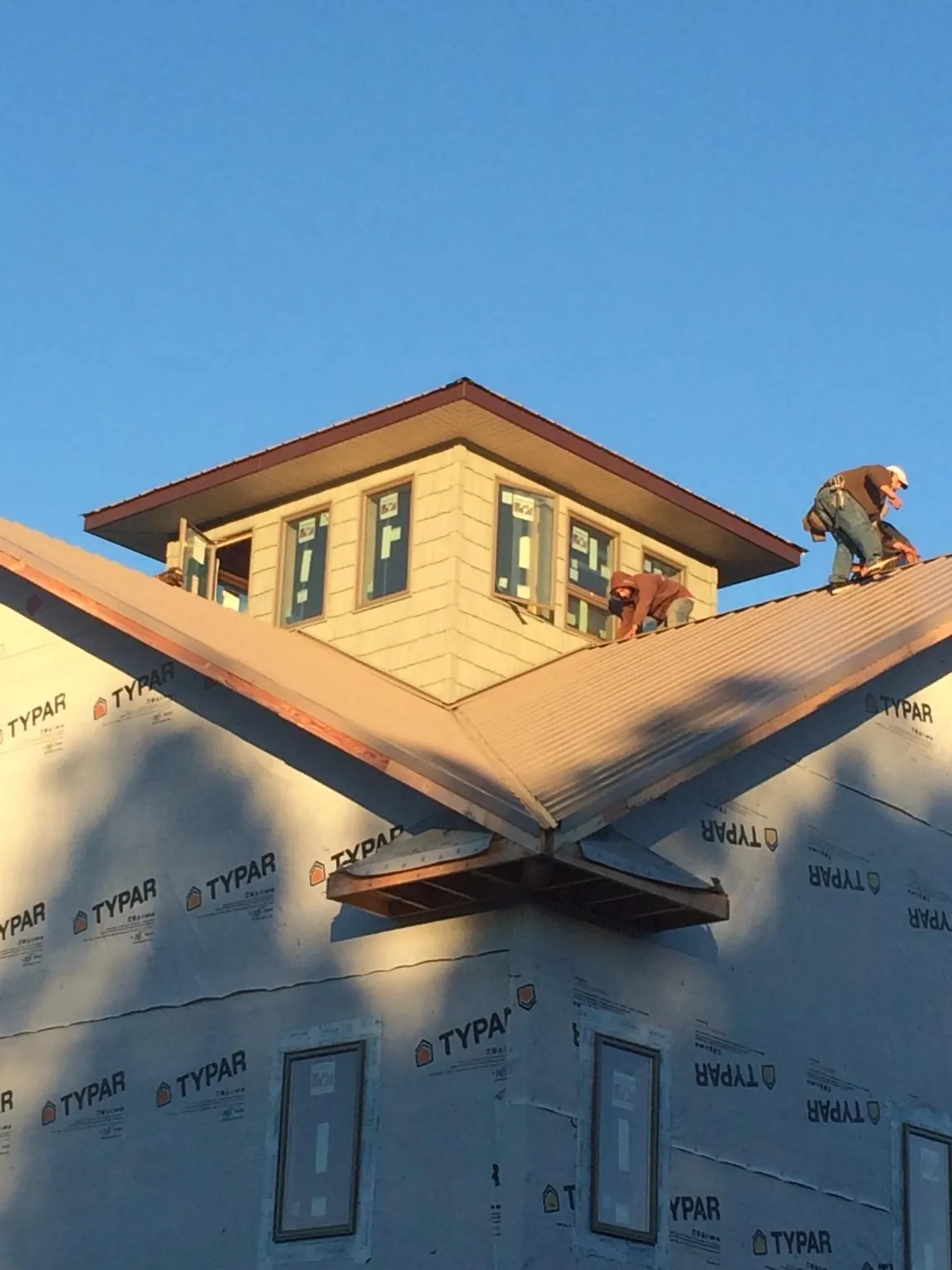 Roofers working around a rooftop cupola on a new metal roof at sunset — Roof Waterproofing in Goodfield by Roofing Brothers